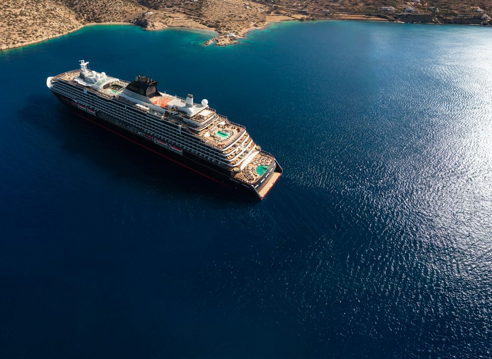 EXPLORA I at anchor in deep blue water off a Greek island, seen from above