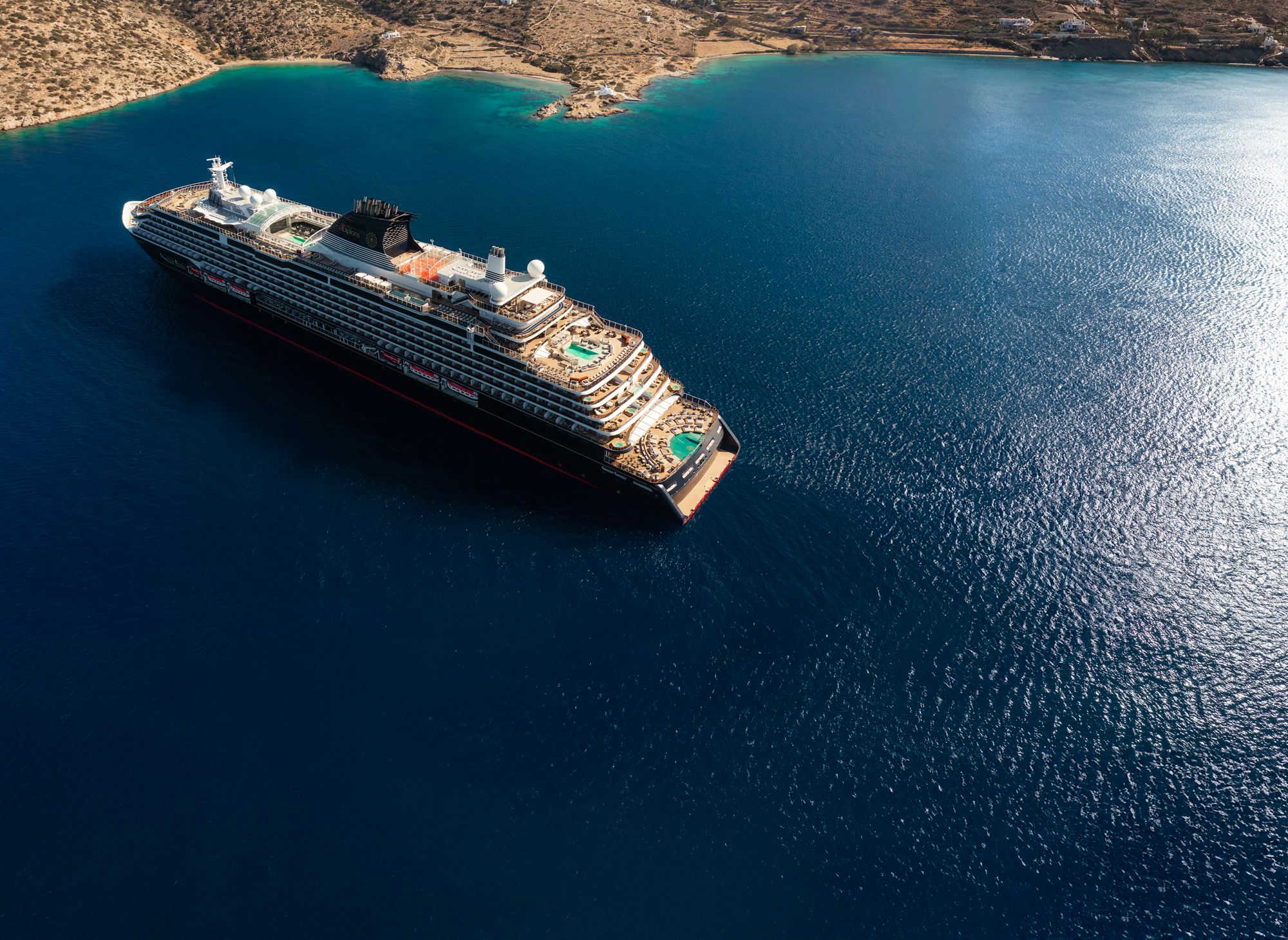EXPLORA I at anchor in deep blue water off a Greek island, seen from above
